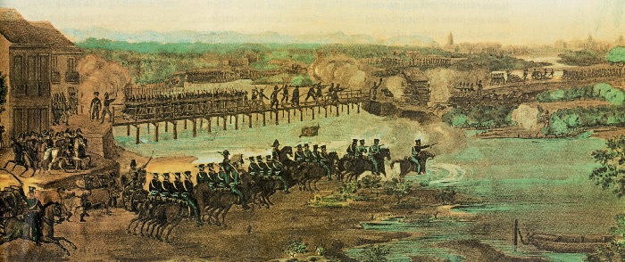 Soldados avançam sobre um rio. Ao fundo, sobre uma ponte, pessoas lutando.