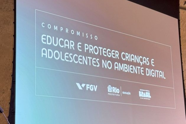 Foto. Painel com projeção. Texto: Compromisso. Educar e proteger crianças e adolescentes no ambiente digital.